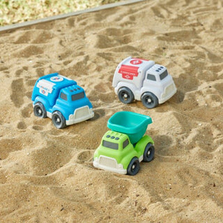 Three toy construction vehicles on a sandy surface