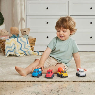 Child playing with toy cars on a carpeted floor with teddy bears in the background.