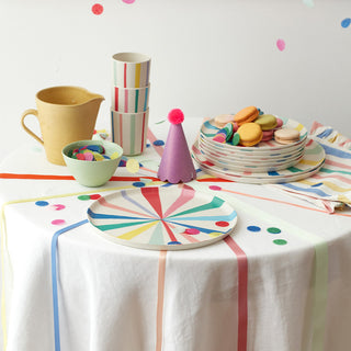 round table with reusable striped tableware, a party hat and confetti