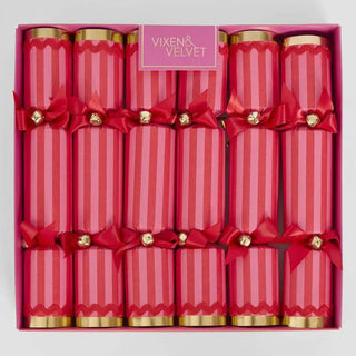 Box of red and pink striped Christmas crackers with gold ends and red bows, branded 'Vixen & Velvet', on a light gray background.