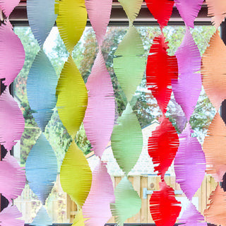 Colorful paper fan decorations hanging indoors with a blurred outdoor background.