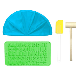 Blue silicone mold, green lettering mold, yellow spatula, and wooden mallet on a white background