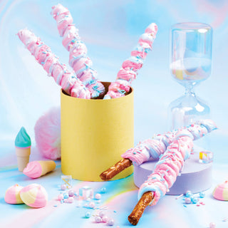 Colorful candy sticks with pink and blue swirls in a yellow container on a pastel background.